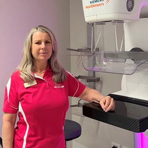 Mammographer in pink shirt standing next to x-ray machine