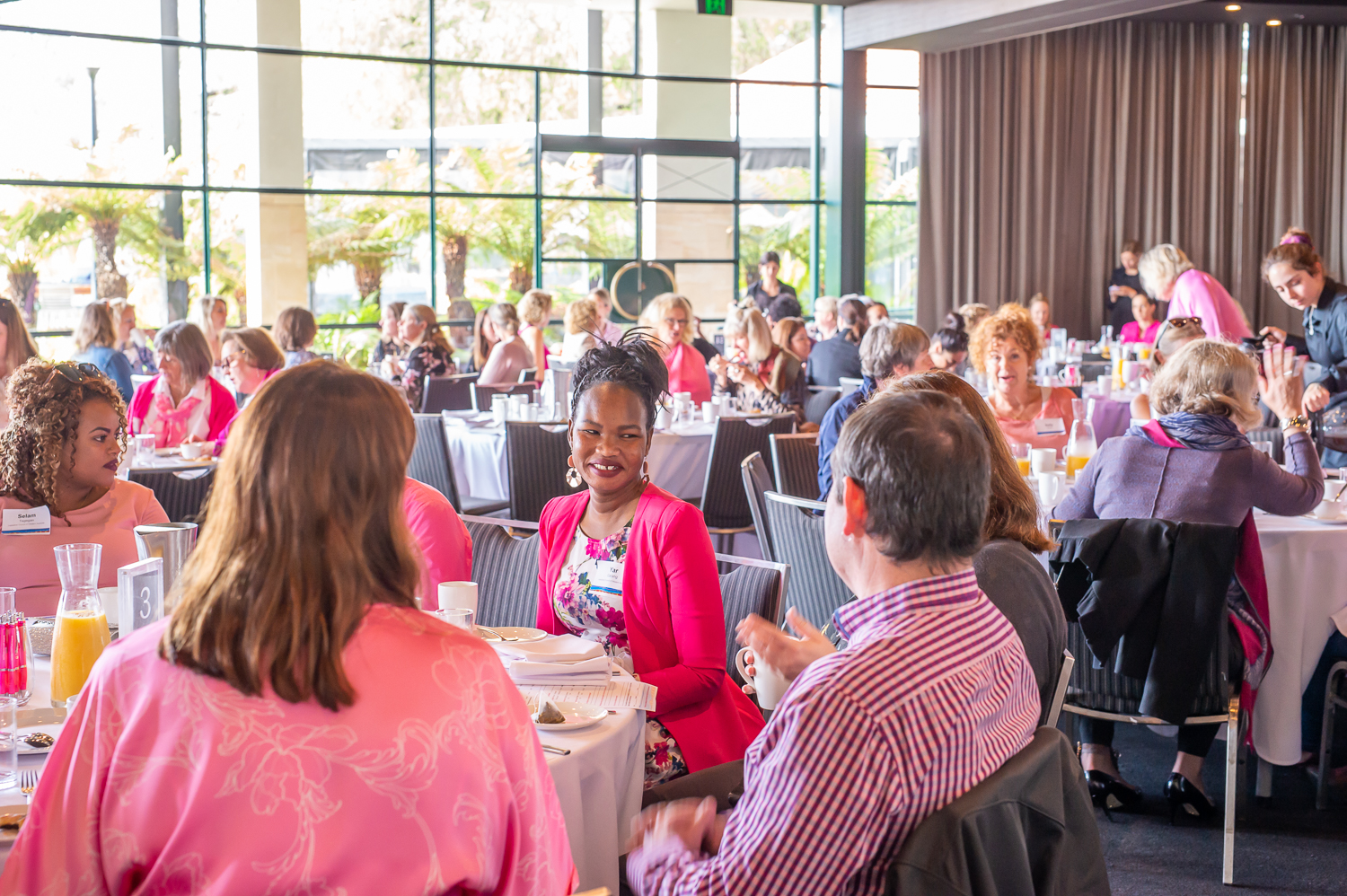 People sitting at tables talking at Pink Ribbon Breakfast