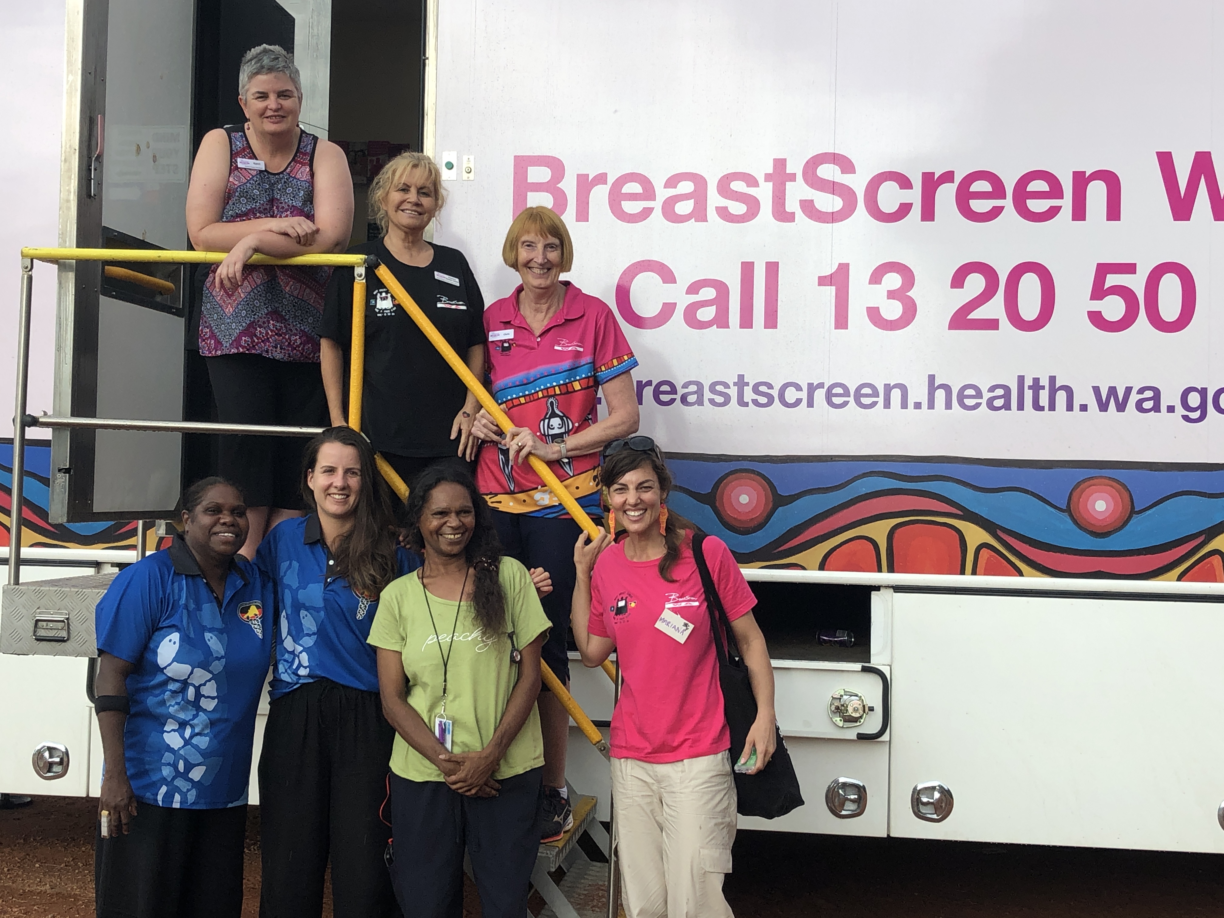 BSWA staff and Bidyadanga community health workers standing on stairs of BSWA mobile screening unit