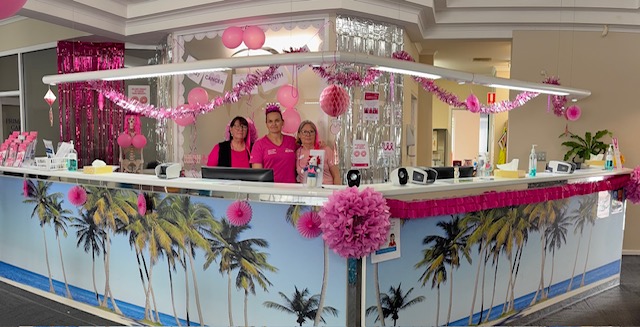 Reception desk of Palm Springs Medical practice with pink decorations and staff smiling behinde desk